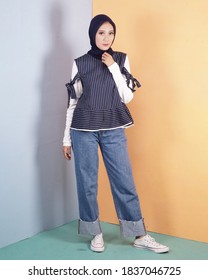 Women In Hijab Are Posing Like Famous Models. The Woman Is Wearing A Blue Striped Shirt And Jeans. Indonesian Hijab Model.	
