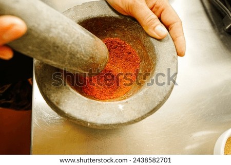 Women hold pestle mortar and ground roasted chills  in the kitchen
