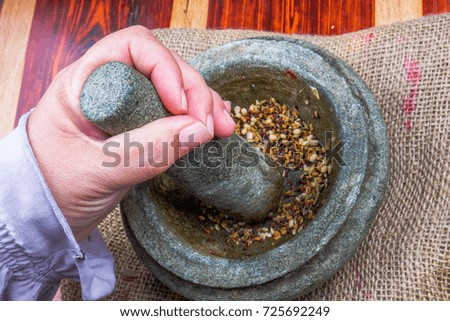 The women hold pestle with mortar and spice on wooden background.