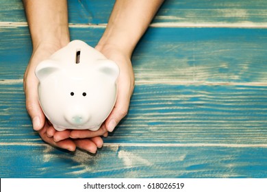 Women Hold A Pig Bank On The Vintage Blue Background, A Saving Money For Future Investment Concept.