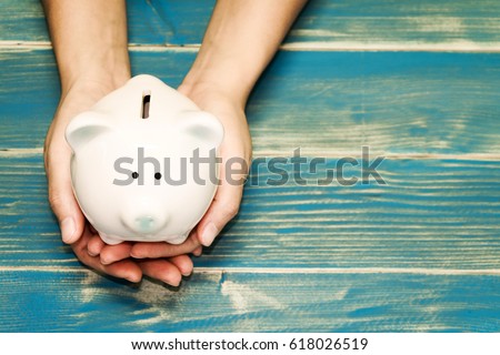 Women hold a pig bank on the vintage blue background, a saving money for future investment concept.