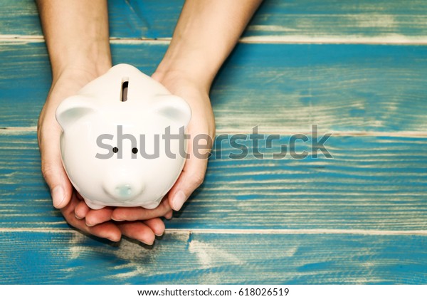 Women hold a pig bank on the vintage blue background, a saving money for future investment concept.