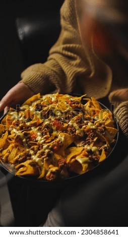 women hold a plate of corn chips nachos with fried minced meat and guacamole with cheese, tomato and dipping sauce