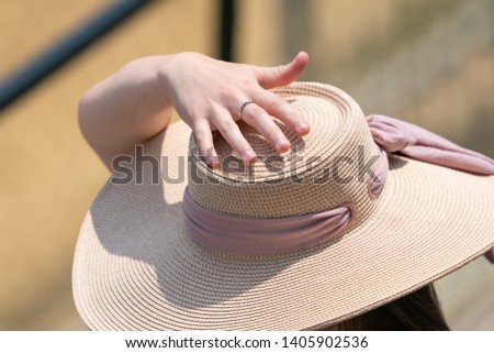 A women holding onto her hat at a horse race.