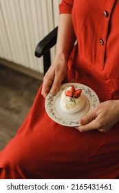 Women Holding Pavlova Dessert With Strawberries And Greens On Top Of Antiqued Patina Table