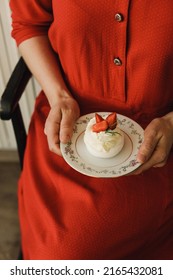 Women holding pavlova dessert with strawberries and greens on top of antiqued patina table