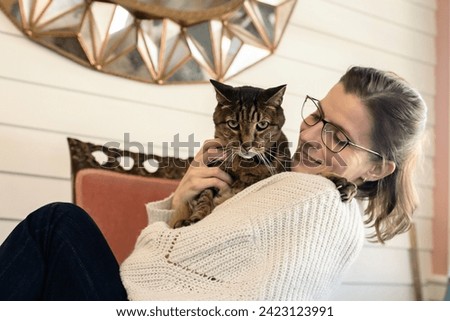Women holding pet cat looking and smiling at him