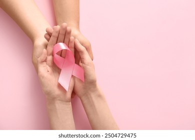 Women holding pink ribbon on color background, closeup. Breast cancer awareness concept