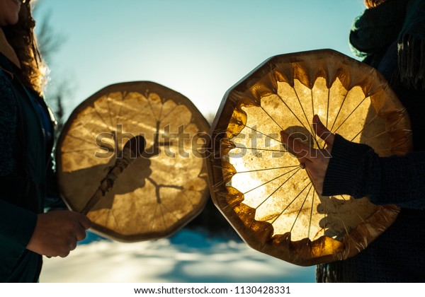 Women holding and playing their sacred drums\
outdoors in the\
wintertime