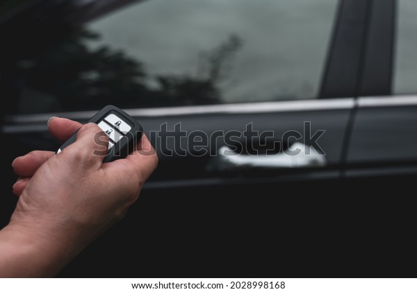 Women holding and pushing a car remote control to\
lock or unlock the car.