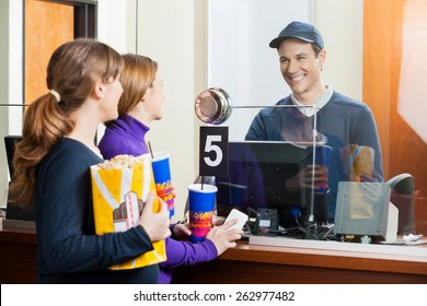 Women Holding Snacks While Buying Movie Tickets From Male Seller At Box Office