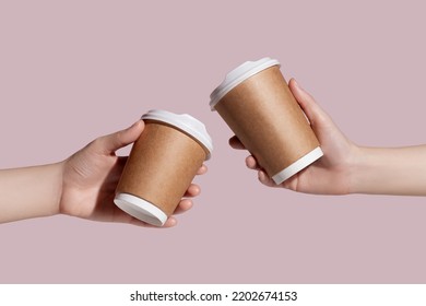 Women holding takeaway paper coffee cup on light pink background. Space for design. Mockup. High quality photo