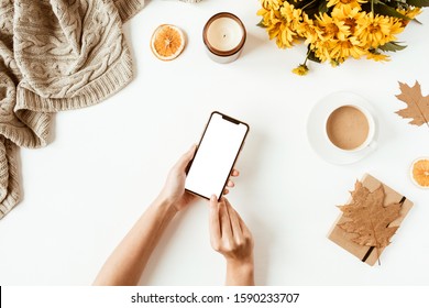 Women home office table desk with blank screen smartphone with copy space. Yellow daisy flowers bouquet, decorations. Flat lay, top view freelance business concept for social media, magazine.