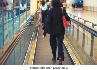 Women at horizontal escalator covered. Moving walkway, moving sidewalk, moving pavement, autopedescalator, walkalator, travelator, horizontal escalator, slidewalk, or moveator at an airport. Toning.