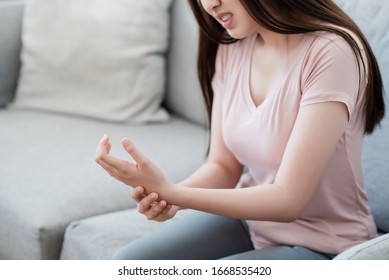 Women Are Hurt Wrist With Face Torture In The Living Room. Healthy, Office Syndrome, Disease, Illness, Sick, Muscle Pain, Overwork, Wrist Ache, Arthritis Concept.
