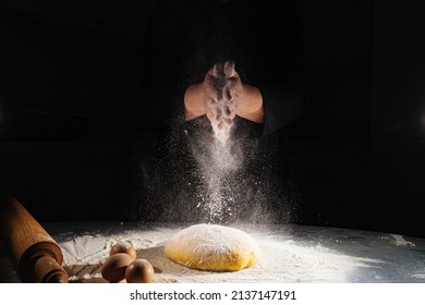 women kneads dough and scatters flour on a black background. eggs on table. the concept of homemade baking and cooking school. recipes for bread, pizza and pies. family business. professional bakery. - Powered by Shutterstock