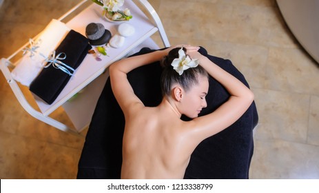 Women Laying Down On The Massage Bed In The Spa With A Flower In Her Hair.