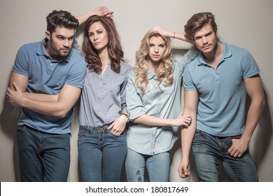 Women Leaning Against Their Handsome Men . Two Couples Of Young Casual People Standing Together In Studio