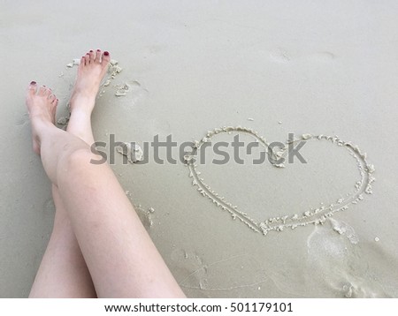 Women legs and heart line on the beach