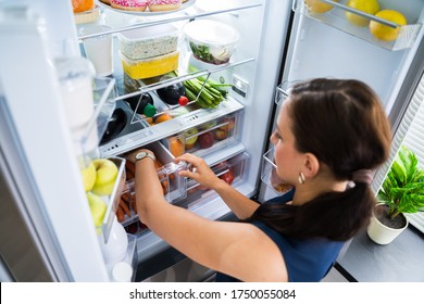 Women Looking For Food Inside Fridge In Kitchen