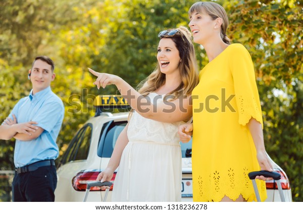 Women with luggage getting into taxi car with the\
driver waiting