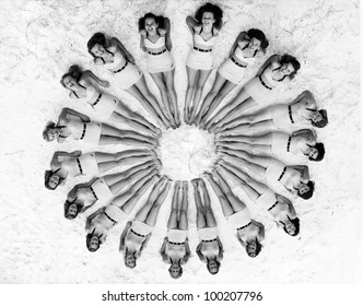 Women lying in circle around beach ball