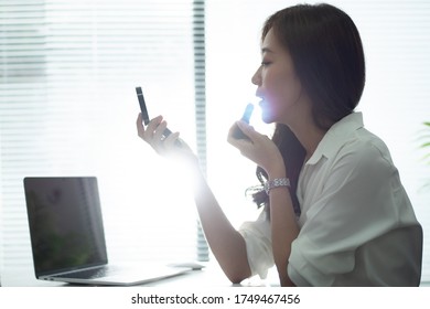 Women are making up while she is working in the office.
