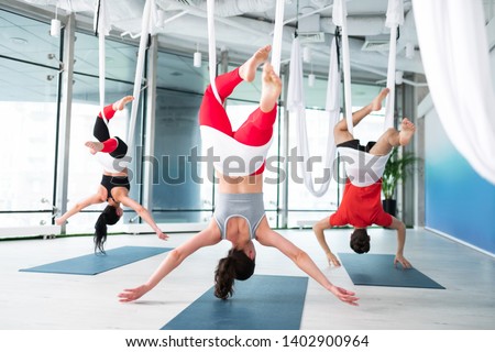 Women and man. Women and man feeling amazing while practicing aerial yoga together in spacious room