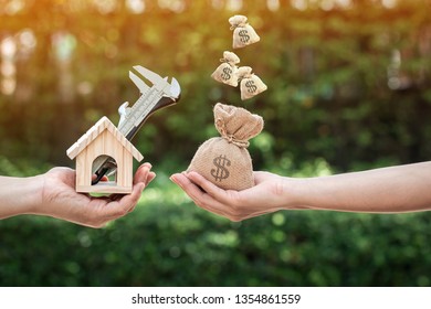 Women and man hand holding a wooden home with repairing and a money bag put together on sunlight in the public park, Saving money and loan for construction real estate and house concept.
