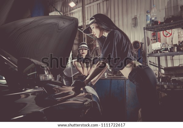 Women mechanics are inspecting the engine at the\
service station.