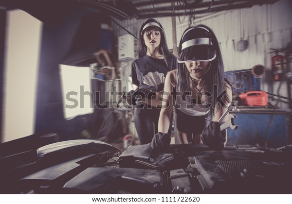 Women mechanics are inspecting the engine at the\
service station.