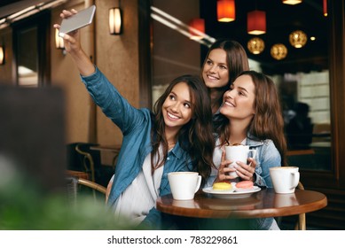 Women Meeting In Cafe. Friends Taking Photo On Phone. Beautiful Smiling Girlfriends Having Coffee Break And Taking Selfies On Mobile Phone In Coffee Shop. High Quality Image. - Powered by Shutterstock