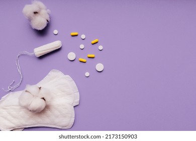 Women Menstrual Cycle Concept. Sanitary Pad, Pills And Tampon Isolated On Purple Background With Cotton.