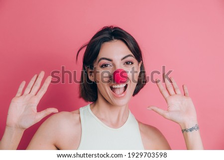Women on pink background pretty funny and smiling young woman wearing clown nose, party mood
