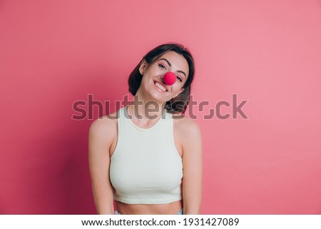 Women on pink background pretty funny and smiling young woman wearing clown nose, party mood