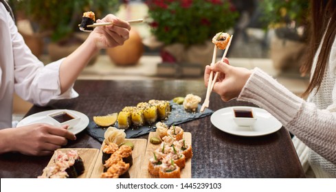 Women ordering four course lunch on special offer. Friends coming to oriental luxury restaurant and enjoying Japanese food. Two elegant colleagues eating sushi set with wasabi and marinated ginger. - Powered by Shutterstock