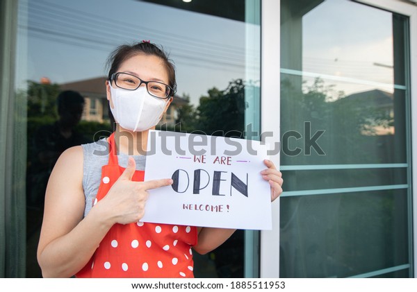 Women Owner\
holds Open sign at front restaurant\
