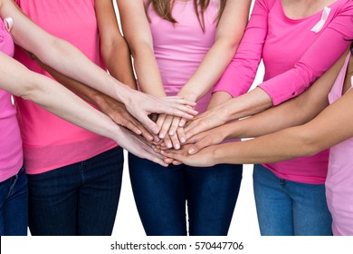 Women in pink outfits joining in a circle on white background for breast cancer awareness - Powered by Shutterstock