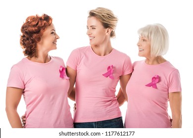 women with pink ribbons standing together and smiling each other isolated on white, breast cancer awareness concept