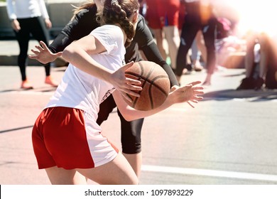 Women play basketball. Group of happy teenage girls in sports uniform, playing basketball outdoors in the city.