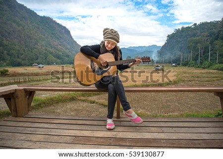 Women playing acoustic guitar in the rice field 
