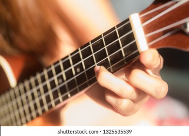 Women playing ukulele music with light of sun in morning