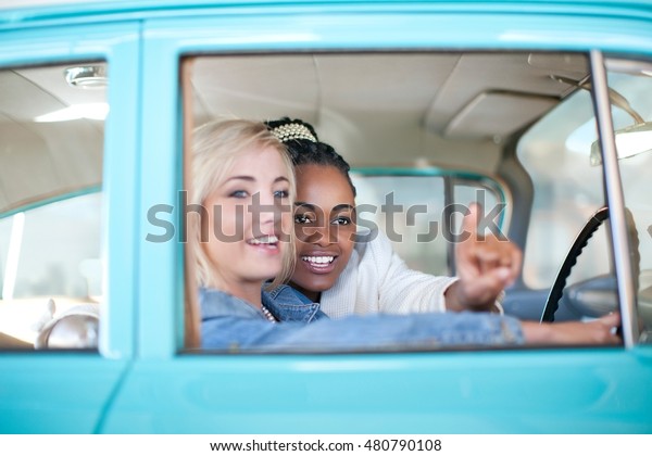 Women pointing out of\
vintage car window