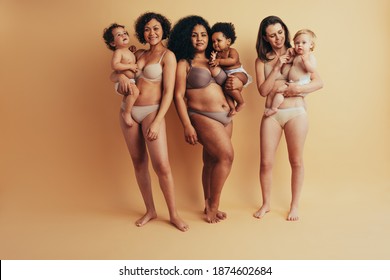 Women With Postpartum Bodies Carrying Their Children. Full Length Of Group Of Mothers With Babies.