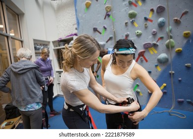 Women preparing equipment at rock climbing wall - Powered by Shutterstock