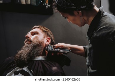 Women Professional Hairdresser Serving Client With Thick Big Beard By Clipper, Handsome Brutal Stylish Young Man Getting Trendy Haircut , Black Barber Shop Room