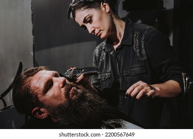 Women Professional Hairdresser Serving Client With Thick Big Beard By Clipper, Handsome Brutal Stylish Young Man Getting Trendy Haircut , Black Barber Shop Room