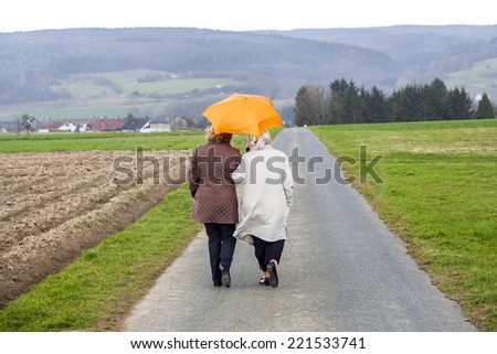 women in rain under an umbrella in rural landscape