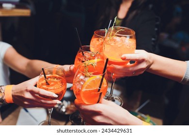 women raising a glasses of aperol spritz at the dinner table - Powered by Shutterstock