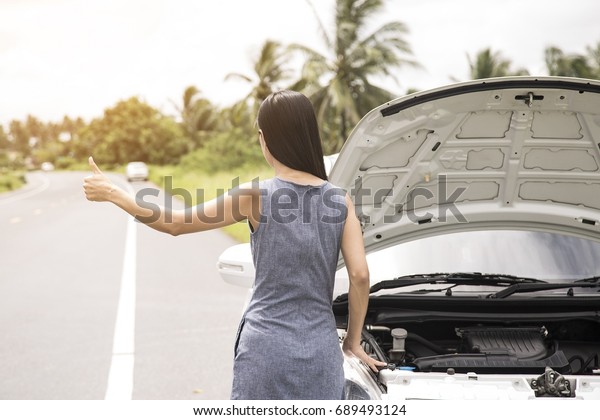 Women are raising their hands for help. The car\
is broken.
